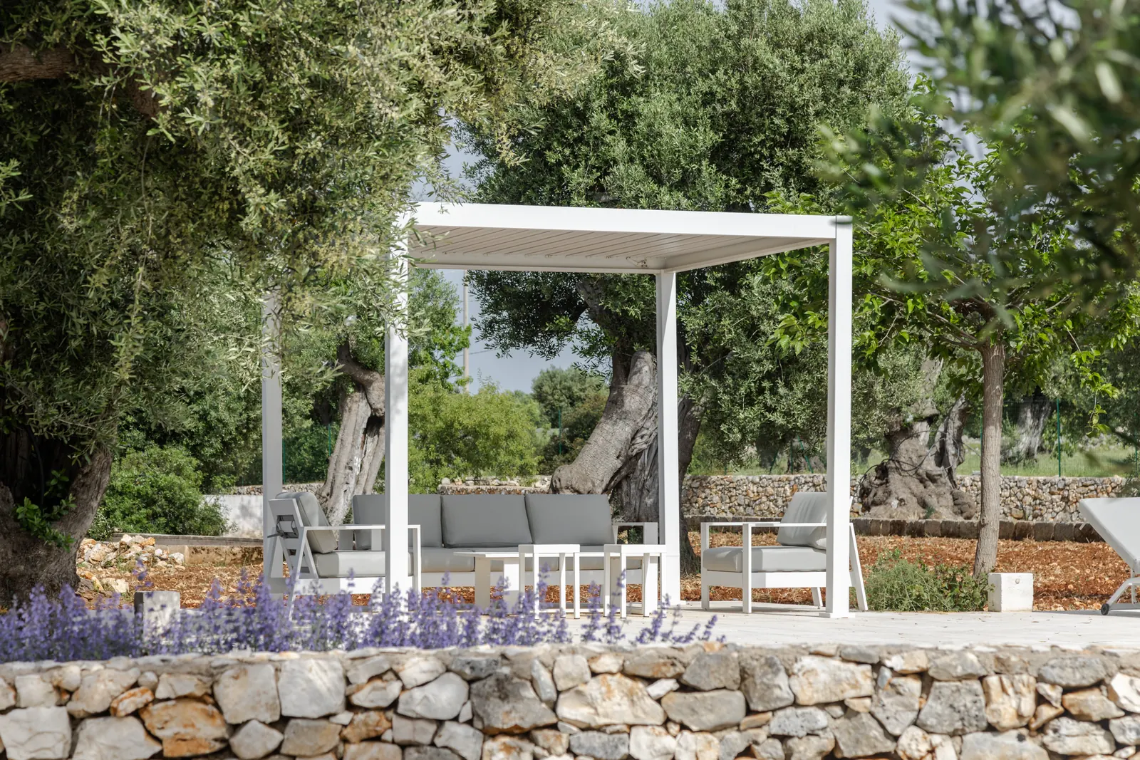 Shaded pergola lounge above lavender and a dry-stone wall