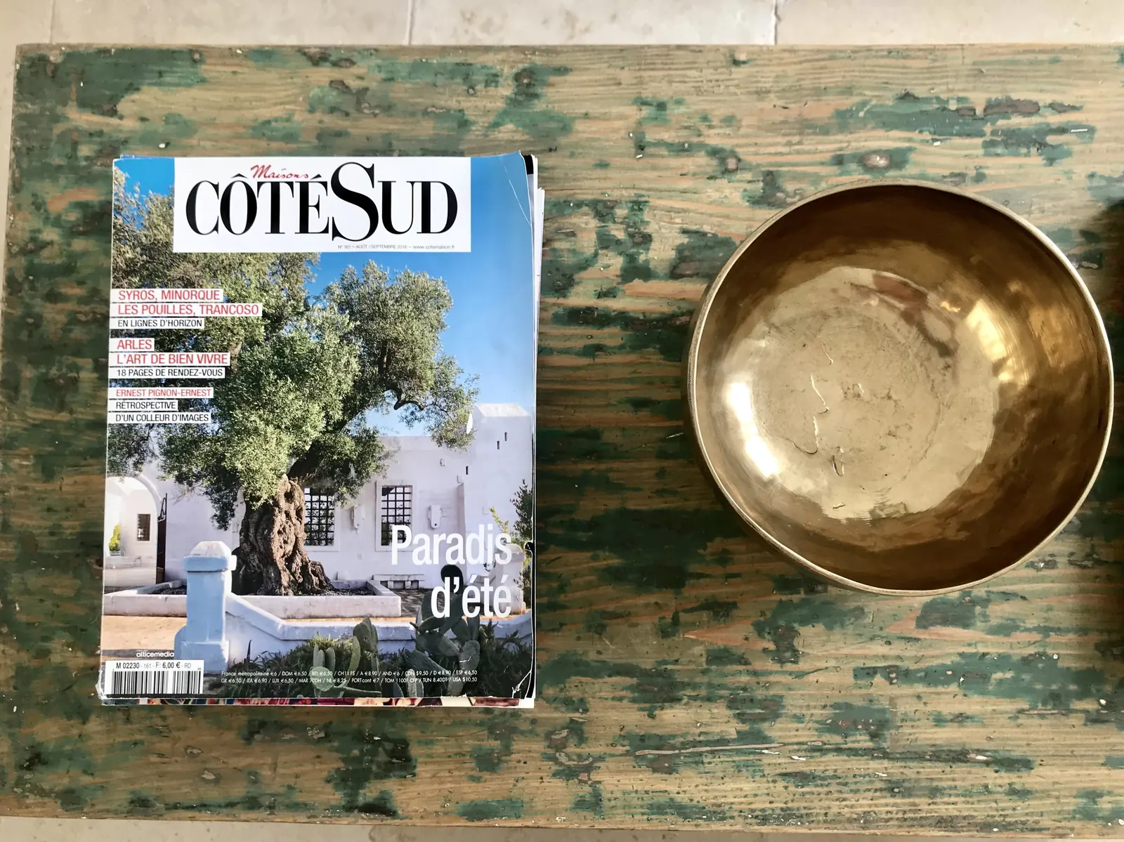 Magazine and brass bowl on a painted table
